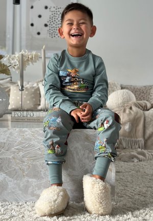 Light blue pajama set featuring playful farm animal patterns; soft texture with matching cuffs and fluffy white slippers. Smooth marble surface.