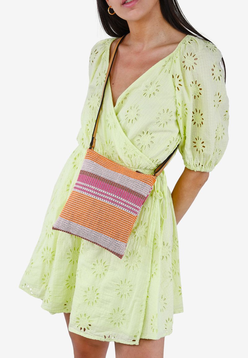 Bolso bandolera tejido en rayas naranja, rosa y blanco. Presenta una superficie texturada y una delgada correa ajustable para un fácil transporte.