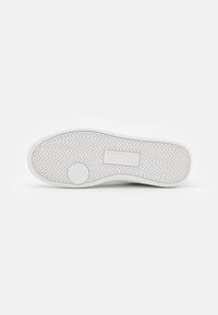 Sola di sneaker bianca con motivo a spina di pesce testurizzato, accento circolare e logo del marchio al centro. Materiale in gomma liscia con bordi rinforzati.