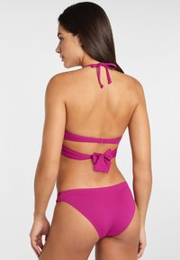 Magenový bikiny s krkom na viazanie, viazané na chrbte. Obsahuje detail mašle a hladký, pružný materiál. Spodný diel s minimálnym pokrytím.