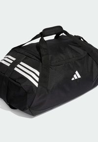 Bolsa de deporte Adidas negra con rayas blancas y logo, asa acolchada, correa de hombro ajustable y bolsillo lateral de malla.
