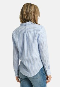 Camicia a maniche lunghe a righe blu e bianche con polsini bottonati e orlo curvo, realizzata in tessuto leggero con una vestibilità casual.
