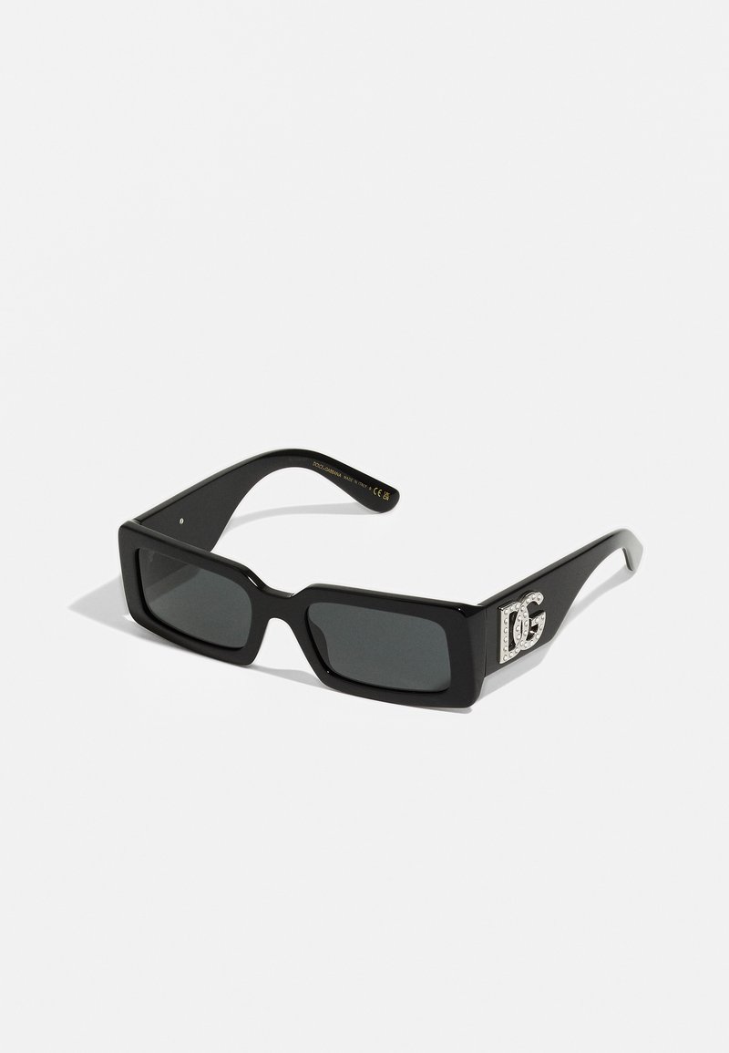 Ochelari de soare rectangulări negri cu lentile întunecate și un cadru gros. Prezintă un detaliu cu logo înfrumusețat cu strasuri pe braț.