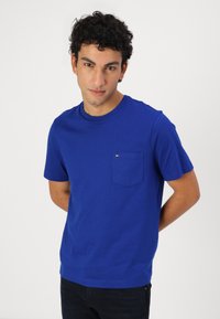 Plava pamučna majica s okruglim izrezom, kratkim rukavima i džepom na prsima koji sadrži mali logo. Slim fit dizajn.