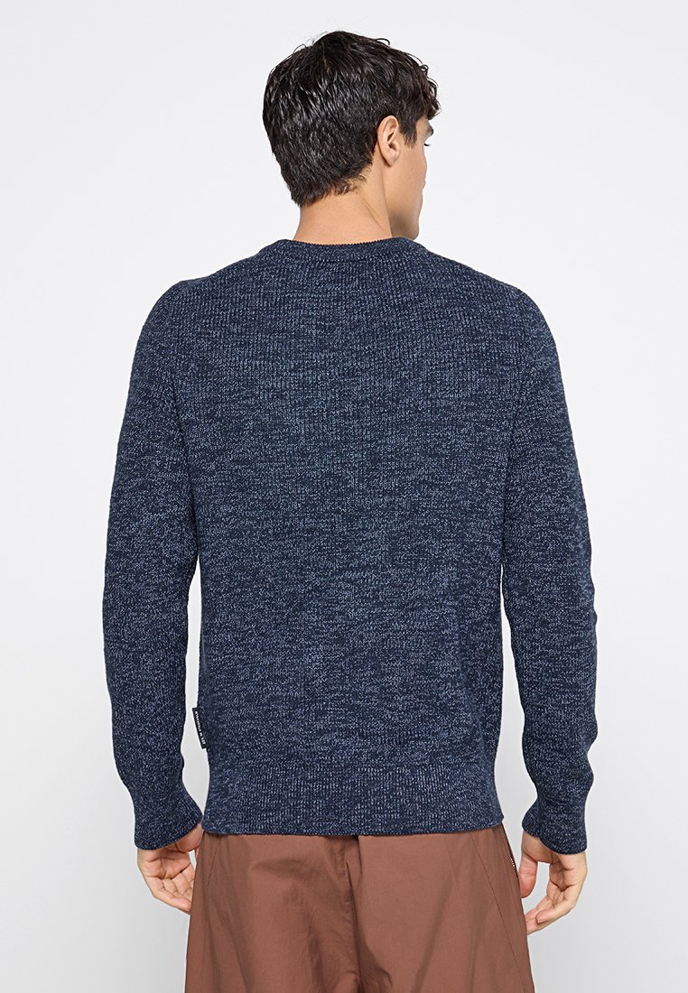 Dunkelblauer Strickpullover mit rundem Halsausschnitt und langen Ärmeln. Die Textur zeigt eine Mischung aus dunklen und hellen Garnen, die ein dezentes Muster erzeugen.