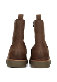 Stivaletti alla caviglia in pelle marrone con finitura liscia, punta arrotondata, linguetta posteriore per facilitare la calzata e cerniera laterale. Suola in gomma robusta con leggero rialzo.
