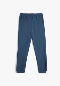 Blå joggingbukser lavet af blødt stof, med elastisk talje og manchetter ved anklerne, med en glat tekstur og enkelt design.