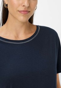 Marineblå bomulds T-shirt med rund halsudskæring og kontrasterende syninger. Korte ærmer og en glat tekstur.
