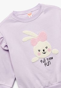 Sudadera lila con un diseño de conejo; presenta un lazo rosa, bordado texturizado y el texto "Diversión a tiempo completo" en negro. Detalle de mangas fruncidas.