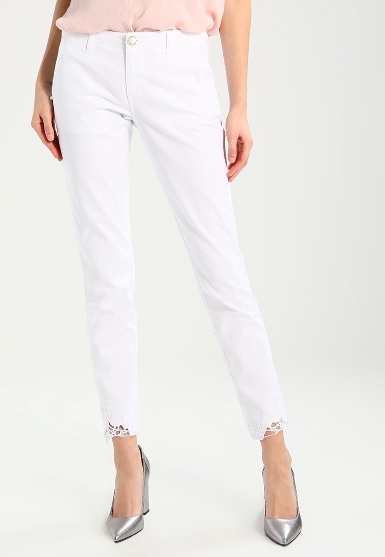 Vita beskurna jeans med spetsdetaljer vid fållen, med en tajt design, femficksstil och frontknäppning.