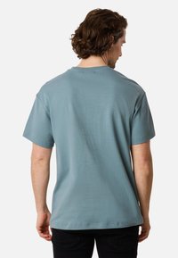 Ljusblå bomulls-T-shirt med korta ärmar, rundad hals och avslappnad passform. Har en slät yta och inga synliga mönster eller detaljer.