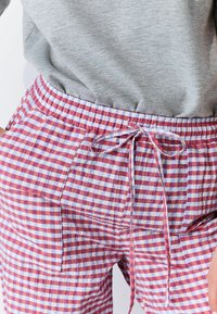 Roze en blauwe geruite broek met een elastische tailleband en trekkoord, voorzien van zijzakken en een lichte stoftextuur.