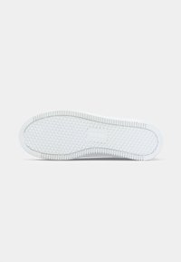 Semelle de sneaker blanche avec motif en losanges et lignes horizontales, présentée à plat sur un fond clair.