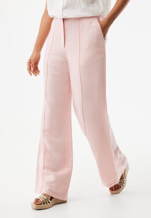 Różowe lniane spodnie o szerokich nogawkach z pionowymi szwami, bocznymi kieszeniami i gładką fakturą, zestawione ze złotymi sandałami na koturnie z paskami.