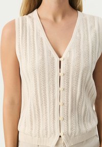 Licht beige gebreide cardigan vest met een V-hals, een verticale streepjespatroon en kleine knoopjes aan de voorkant. Geribbelde zoom en armsgaten.