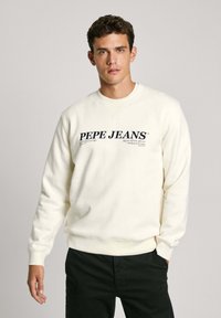 Krmově bílá mikina se širokým výstřihem, na které je velké černé logo "PEPE JEANS" napříč hrudníkem a pružné manžety a spodní lem.