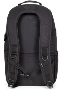 Mochila de tela negra con correas acolchadas, un interior espacioso, correas laterales ajustables y una textura suave. Sin hardware ni patrones visibles.