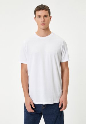 Witte katoenen t-shirt met een ronde hals en korte mouwen, met een soepele textuur en een relaxed fit. Draagt met blauwe spijkerbroek.