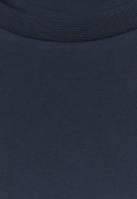 Mörkblå bomullstyg med en slät yta, med en ribbad halslinning. Materialet är lätt och enhetligt i färgen.