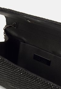 Clutch bag nera con texture e finiture metalliche, dotata di un interno liscio e di una piccola tasca per riporre oggetti. Design compatto e versatile.