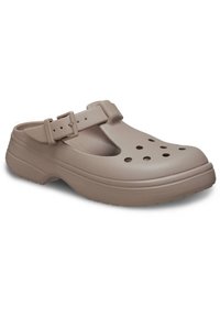 Zoccoli in plastica beige con fori di ventilazione, una cinghia regolabile con fibbia, suola testurizzata e design arrotondato. Leggeri e resistenti.