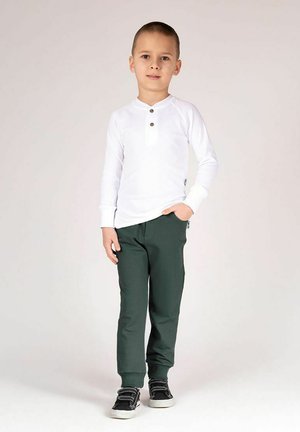 Biała koszula z długim rękawem, zapinana na trzy guziki, zestawiona z ciemnozielonymi spodniami. Strój charakteryzuje się wygodnym krojem i prostym designem. Dołączone czarne trampki.