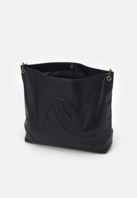 Czarna skórzana torba typu tote z wytłoczonym logo, miękką fakturą, otwartym wierzchem i złotymi akcentami metalowymi. Przestronne wnętrze z minimalistycznymi detalami.