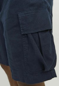 Pantaloni cargo blu navy realizzati in tessuto leggero, con una tasca a soffietto sul lato e orli arrotolati per una vestibilità rilassata.