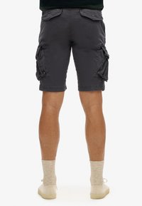 Cargo shorts in donkergrijs katoen met meerdere zijzakken, een relaxte pasvorm en zichtbare stikseldetails, gecombineerd met beige sokken en schoenen.
