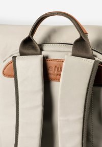Light beige backpack featuring a textured fabric, dark green straps, and a brown leather accent with embossed brand logo.