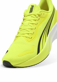 Scarpa da corsa Puma in materiale mesh giallo brillante. Presenta accenti e lacci neri, con una suola imbottita e un design aerodinamico.
