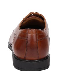 Scarpa in pelle marrone con punta arrotondata, dettagli cuciti, texture liscia e suola in gomma nera.