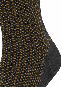 Chaussettes grises avec un motif texturé présentant des carrés et des points jaunes et gris, en tissu lisse, avec une zone de talon et d'orteil renforcée.