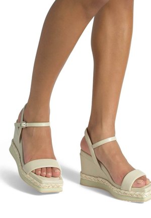 Sandali wedge beige con un dettaglio in corda intrecciata testurizzata nella suola, doppi cinturini alla caviglia e design open-toe. Superficie liscia, stile minimalista.