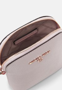 Piccola pochette in pelle rosa con zip dorata, dotata di una tasca interna e logo impresso. Texture liscia con forma strutturata.