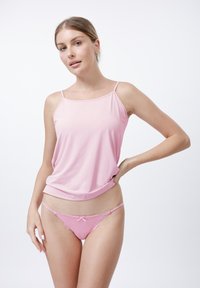 Roze cami-top met dunne bandjes, gemaakt van zachte stof, gecombineerd met een bijpassende roze slip met kantversiering en een strikdetail.