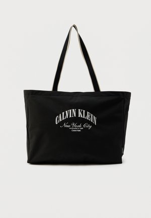 Mustast vastupidavast materjalist käekott, millel on valgete tähtedega kiri "CALVIN KLEIN New York City"; kahekordsete sangade ja ristkülikukujulise kujundusega.