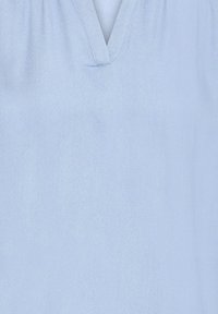 Tissu bleu clair avec une texture douce et un détail de couture en V au centre supérieur.