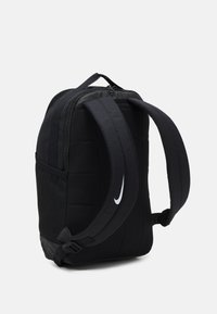 Svart ryggsäck med vadderad tyg, justerbara remmar, dragkedja upptill och sidoficka i nät. Har en vit Nike-logotyp på ena sidan.
