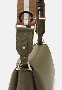 Borsa a mano in pelle verde oliva con un design strutturato, caratterizzata da una superficie texturizzata, accessori in oro e una tracolla regolabile con motivo.