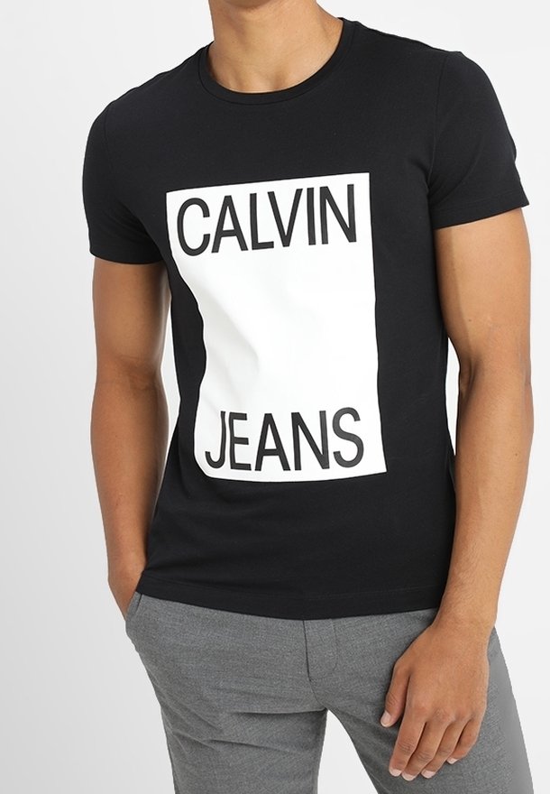 Zwarte katoenen t-shirt met een witte rechthoekige graphic met daarop "CALVIN JEANS" in vetgedrukte zwarte letters. Korte mouwen en een getailleerd ontwerp.