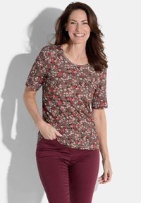 Brown floral print short-sleeve top with a round neck; features red and white flowers on a textured background. Paired with burgundy pants.