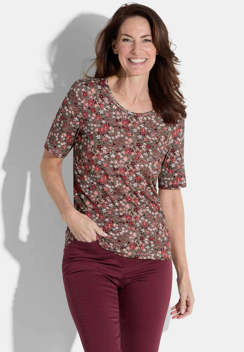 Brown floral print short-sleeve top with a round neck; features red and white flowers on a textured background. Paired with burgundy pants.