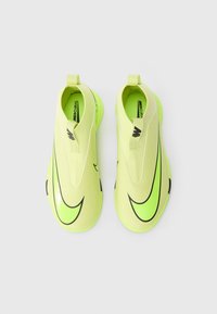 Zapatos Nike Mercurial de un amarillo neón con una textura suave, diseño tipo slip-on, acentos en negro y suela redondeada. Sin cordones, con la marca en la parte superior.