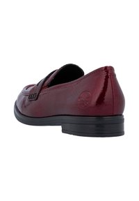 Mocassin en cuir bordeaux brillant avec semelle noire, talon bas et logo embossé sur le talon, vu d'un angle latéral arrière.