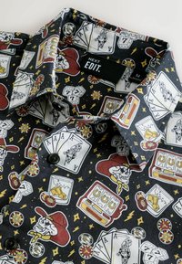 Kurzarmhemd aus schwarzem Stoff mit einem bunten Glücksspiel-Motiv, das Würfel, Karten und Totenkopf-Grafiken beinhaltet.