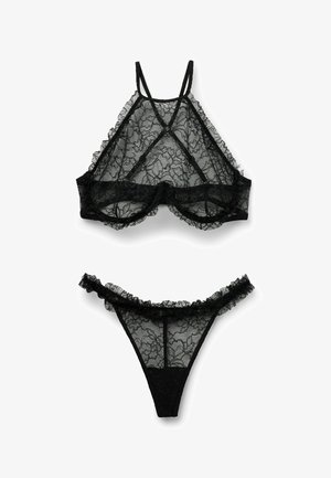 Czarny zestaw bielizny koronkowej z przejrzystymi kwiatowymi wzorami, w skład którego wchodzi biustonosz typu bralette z regulowanymi ramiączkami oraz pasujący majteczki z falbankami.