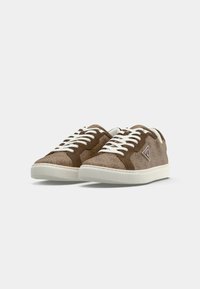 Baskets en daim marron avec lacets blancs, présentant un motif texturé et un logo sur le côté. Semelle épaisse en caoutchouc blanc pour le confort.
