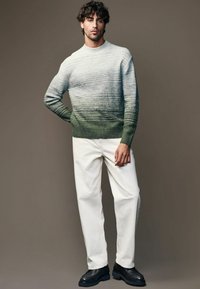Suéter de punto en gradiente de teal a blanco, con rayas horizontales texturizadas; combinado con pantalones blanco roto y zapatos negros.