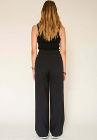 Pantalons à larges jambes rayés noirs avec une taille haute, dotés de poches arrière et d'une texture de tissu lisse. Présentés vue de dos.